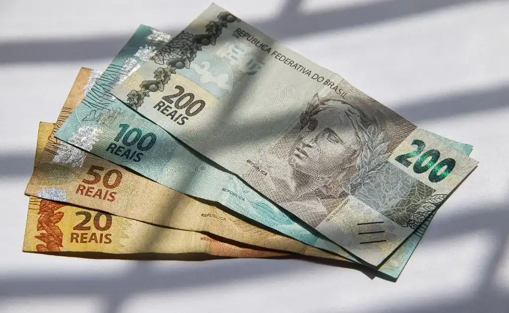 Cédulas de 20, 50, 100 e 200 reais dispostas sobre uma superfície branca