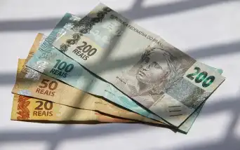 Cédulas de 20, 50, 100 e 200 reais dispostas sobre uma superfície branca