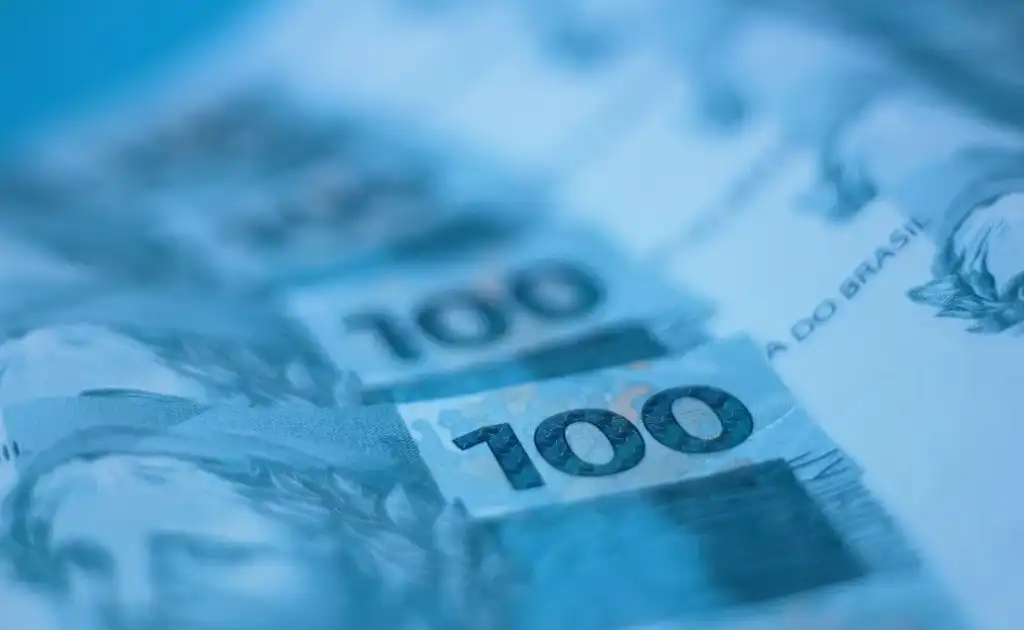 Notas de 100 reais em close, com tom azulado