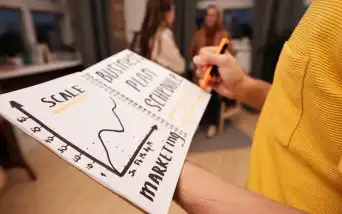 Pessoa organizando ideias de negócio em um quadro de planejamento